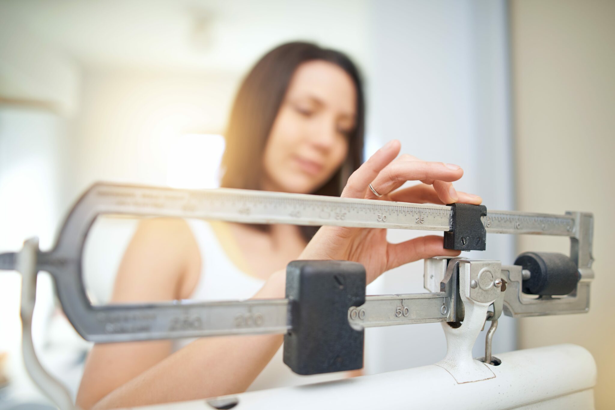 Shot of a young woman weighing herself on a scale